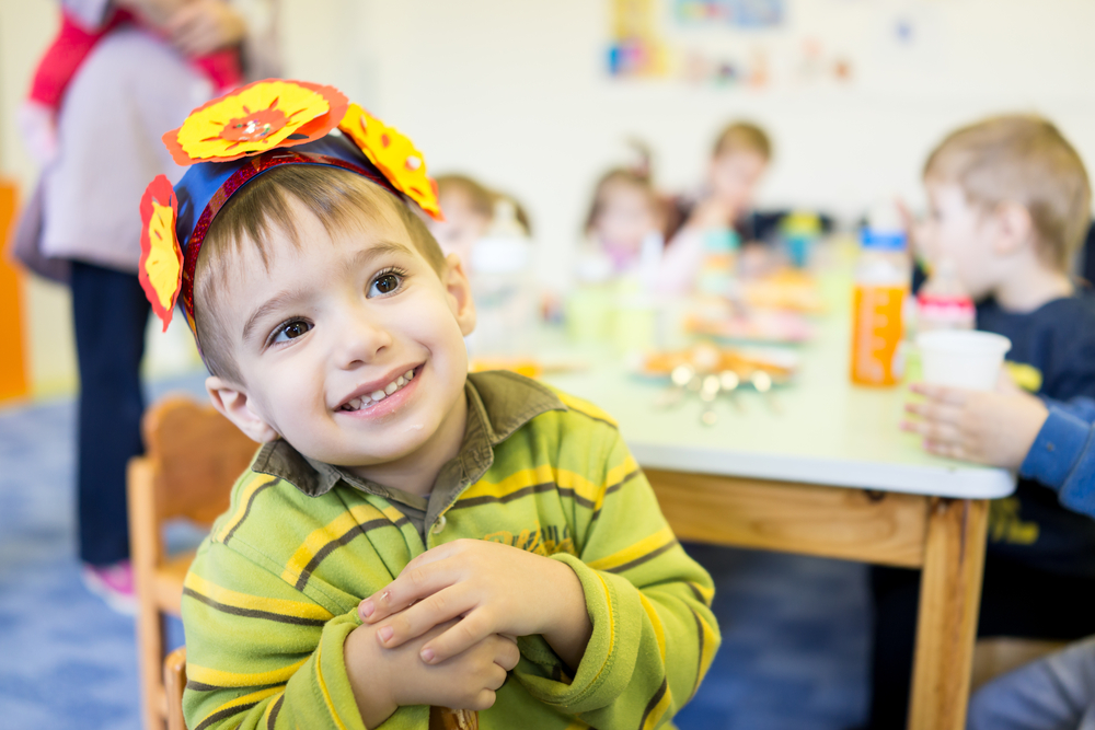 young boy eats with his friends at a child care program