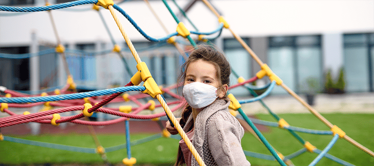 Child playing outside wearing facemask