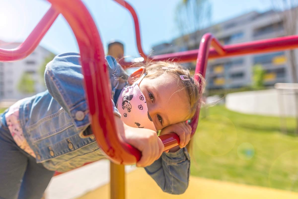 girl in mask plays on playground