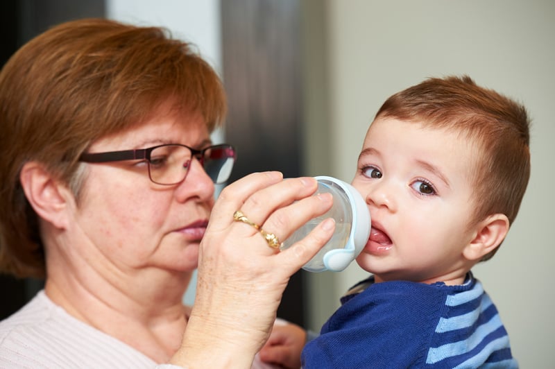 teacher gives bottle to toddler