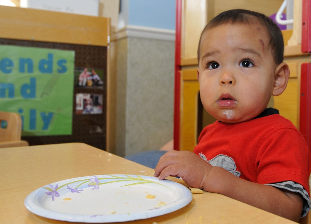 A toddler eats in a child care center