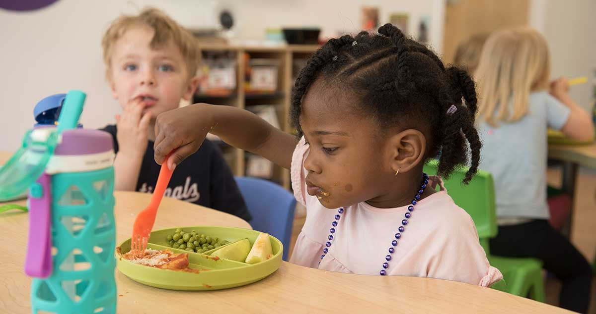 young girl eats lunch at table