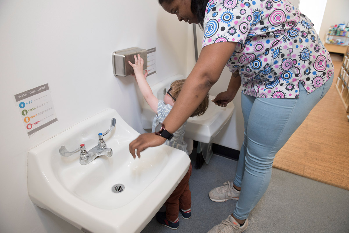 An ECE professional helps a child use soap